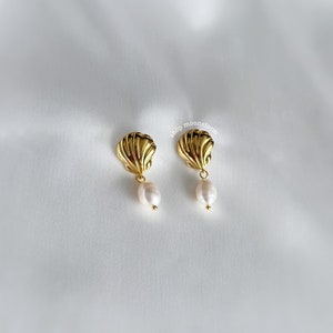 May include: A pair of gold shell earrings with a pearl dangling from each shell.