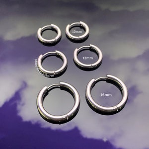 May include: Four silver hoop earrings of different sizes. The earrings are 10mm, 12mm, and 16mm in diameter. The earrings are on a reflective surface.