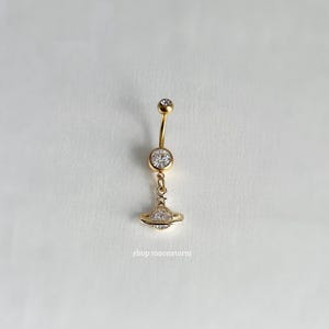 May include: Gold belly button ring with a clear crystal orb and a charm of a gold orb with a star and clear crystals.