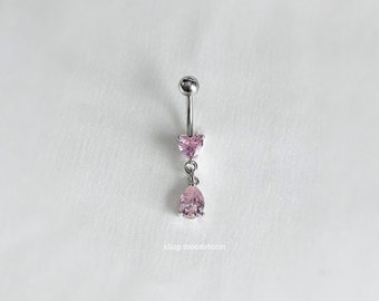 May include: A silver belly button ring with a pink heart and teardrop shaped crystal accents.  The ring is on a white background.