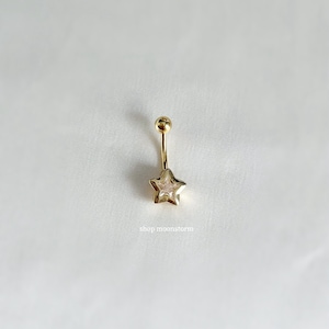 May include: Gold belly button ring with a clear star-shaped charm. The star has a smaller star inside.
