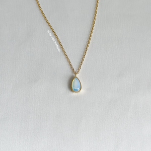 Puede incluir: Un delicado collar de cadena dorada con un colgante de ópalo en forma de lágrima.