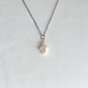 Puede incluir: Un collar de cadena de plata con un colgante de cruz de perla.