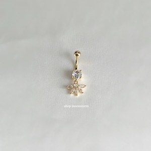 May include: Gold belly button ring with a clear crystal center and a cluster of smaller clear crystals around it.