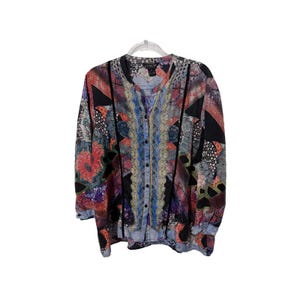 May include: A long-sleeved button-down shirt featuring a vibrant, multi-colored patchwork pattern with geometric and floral motifs. The garment includes a central vertical panel with intricate lace-like detailing and black trim accents.