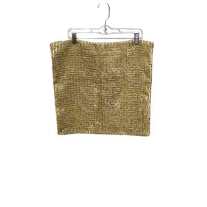 May include: A rectangular pillow cover in a metallic gold hue featuring a raised, textured geometric maze pattern. The fabric has a velvet-like appearance with a repeating square motif across the entire surface, suspended from a clear hanger.