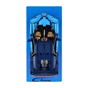 May include: Overhead shot of a blue and dark blue model car on a blue background. The model car features open doors and a detailed interior. The word "Chiron" is written in a cursive font at the bottom of the image.