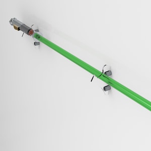 May include: A green lightsaber with a silver handle is mounted on a clear acrylic wall mount. The lightsaber is held in place by two clear acrylic brackets.