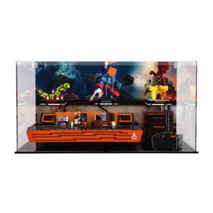May include: A clear acrylic display case with a black base, showcasing a LEGO® Ideas Arcade set. The set features a retro arcade cabinet with a variety of classic video games, including Pac-Man, Space Invaders, and Donkey Kong. The case also includes a joystick and a set of arcade tokens.