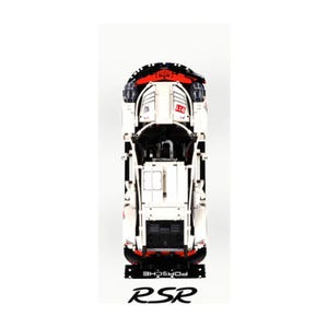 May include: A white and black Porsche RSR model car with red detailing. The car features the number 911 and the word "PORSCHE". The letters "RSR" are displayed at the base of the car.