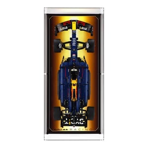 May include: A blue and yellow Formula One race car model with the text "Red Bull Racing" and "Bybit" on the side. The car is displayed in a clear acrylic case with a gold background.