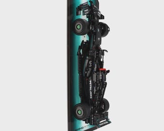 May include: A black and green Lego model of a Formula 1 race car, mounted on a black and green display stand. The car has the Petronas logo on the side.