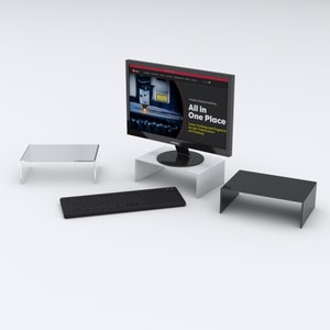 May include: A black computer keyboard, a clear acrylic monitor stand, a white acrylic monitor stand, and a black acrylic monitor stand. The monitor stand is on a white surface. The computer monitor is displaying a website with the text "All in One Place" and "Laser Cutting and Engraving, Acrylic Fabrication, UV Printing".