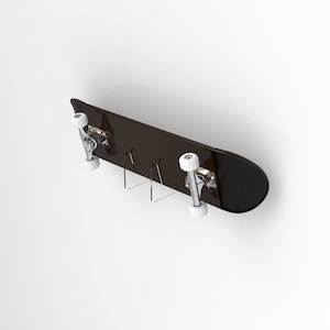 May include: A black skateboard with white wheels is mounted on a clear acrylic wall mount. The skateboard is hanging horizontally on a white wall.
