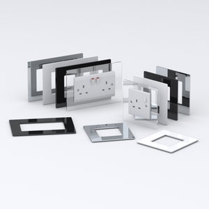 May include: A selection of wall plates in different colours and materials, including black, white, silver, and glass. The plates are designed to fit standard electrical outlets and switches.