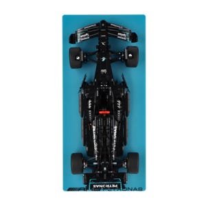 May include: A black Formula 1 racing car model, seen from above, rests on a rectangular blue surface. The car has sponsor logos and the text "PETRONAS". The tyres are black, and the car's body is highly detailed.