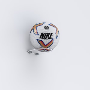 May include: A white football with gold and blue accents and the Nike logo. The ball is mounted on a clear acrylic wall mount.
