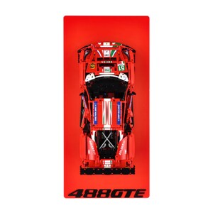May include: A red toy race car with white and green details, displaying the number 51. The car has sponsor logos and the text "488GTE" at the bottom. The car is set against a red background.