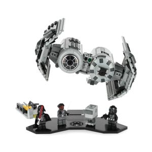 May include: A Lego Star Wars Tie Fighter model in black and grey. The model is displayed on a black stand with three minifigures: Darth Vader, a TIE pilot, and a Rebel pilot.
