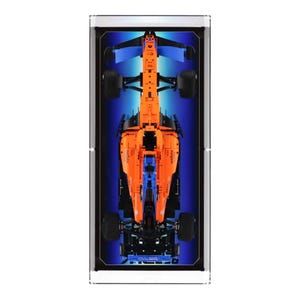 May include: A Lego McLaren Formula 1 race car model in orange and blue, displayed in a clear acrylic case with a black background.