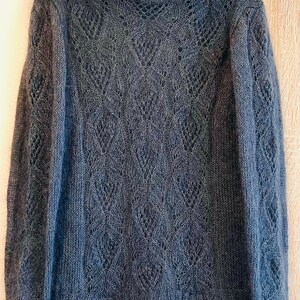 K&ouml;nnte beinhalten: Ein dunkelgrauer, offener Strickpullover mit einem zarten Spitzenmuster. Der Pullover hat lange &Auml;rmel und einen runden Ausschnitt.
