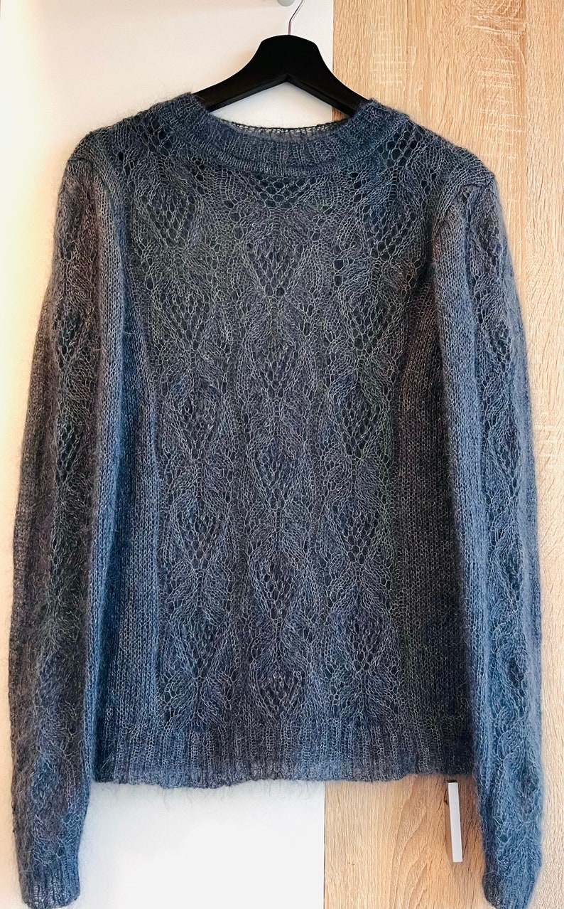 K&ouml;nnte beinhalten: Ein dunkelgrauer, offener Strickpullover mit einem zarten Spitzenmuster. Der Pullover hat lange &Auml;rmel und einen runden Ausschnitt.