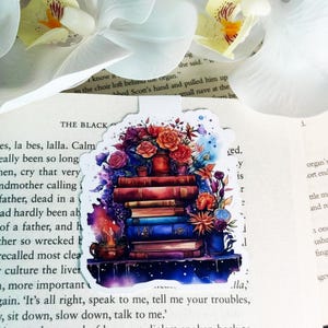 May include: A colorful sticker featuring a stack of books with flowers and a teacup. The sticker has a watercolor effect and a starry background. The text on the sticker reads "The Black"