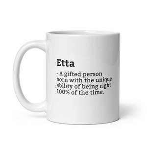 May include: White ceramic mug with the name "Etta" printed in black, along with a definition. The definition describes Etta as a gifted person who is always right. The mug has a curved handle.