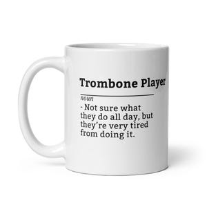 May include: White ceramic mug with the text "Trombone Player" and a definition. The definition reads: "- Not sure what they do all day, but they're very tired from doing it."