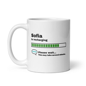 May include: White ceramic mug with a black graphic that says "Sofia is recharging" with a green progress bar and the text "Please wait... This may take several minutes."