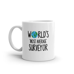Op de afbeelding: Witte keramische mok met een zwarte afbeelding waarop "World's 'Most Average' Surveyor" staat, met een kleine blauwe en groene wereldbol boven de tekst.