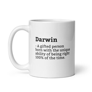 Op de afbeelding: Witte keramische mok met de naam "Darwin" in zwarte letters, samen met een definitie. De definitie luidt: "- Een begaafd persoon geboren met het unieke vermogen om 100% van de tijd gelijk te hebben."