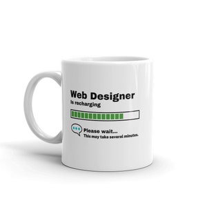 Può includere: Tazza in ceramica bianca con una grafica nera e verde che recita "Web Designer is recharging..." con una barra di avanzamento e un fumetto che dice "Si prega di attendere... Questo potrebbe richiedere diversi minuti."