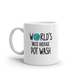Könnte beinhalten: Weiße Keramiktasse mit einer schwarzen Grafik, auf der "WORLD'S 'MOST AVERAGE' POT WASH" steht, mit einem kleinen Bild eines blauen und grünen Globus.