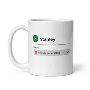 May include: White ceramic mug featuring the name "Stanley" and a green "S" logo. The status "Mentally out of office" is displayed below the name in a grey box with a red circle.