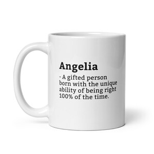Pode incluir: Caneca de cerâmica branca com o nome "Angelia" impresso em preto, juntamente com uma definição. A definição diz: "Uma pessoa talentosa nascida com a capacidade única de estar certa 100% do tempo."