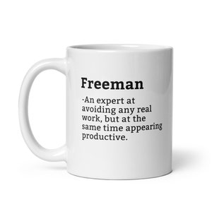 Pode incluir: Caneca de café de cerâmica branca com uma definição de texto preto da palavra "Freeman" como um especialista em evitar qualquer trabalho real, mas ao mesmo tempo parecer produtivo.