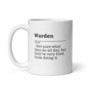 Puede incluir: Taza de cerámica blanca con la palabra "Warden" en negro y una definición. La definición dice: "- No estoy seguro de lo que hacen todo el día, pero están muy cansados de hacerlo."