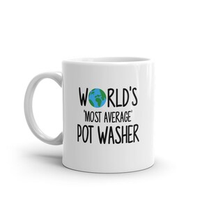 Könnte beinhalten: Weiße Keramiktasse mit einer schwarzen Grafik, auf der "World's 'Most Average' Pot Washer" steht, mit einem Cartoon-Bild der Erde.