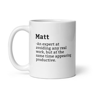May include: White ceramic mug with a black text design that reads "Matt - An expert at avoiding any real work, but at the same time appearing productive."