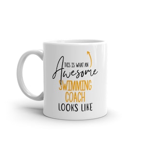 Pode incluir: Caneca de café de cerâmica branca com um design preto e dourado. O texto na caneca diz "This is what an awesome swimming coach looks like".
