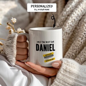 May include: White ceramic mug with the text "ONLY THE BEST FOR DANIEL" in black. A yellow "REDUCED" sticker with a barcode and the price "NOW $0.99" is on the mug. The top of the mug has the text "PERSONALIZED FILL IN YOUR NAME".