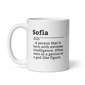 Könnte beinhalten: Weißer Keramikbecher mit dem Namen "Sofia" in Schwarz aufgedruckt, zusammen mit einer Definition. Die Definition beschreibt Sofia als eine Person mit extremer Intelligenz, oft als Genie oder gottähnliche Figur angesehen.