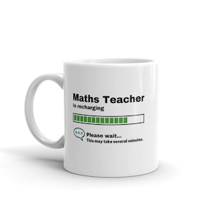 May include: White ceramic mug with a black and green design. The mug reads "Maths Teacher is recharging... Please wait... This may take several minutes."