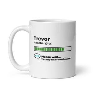 May include: White ceramic coffee mug with a black graphic that says "Trevor is recharging" with a green progress bar and the text "Please wait... This may take several minutes."