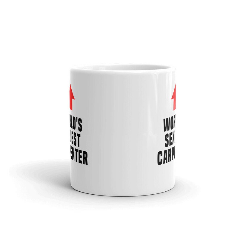 May include: White ceramic coffee mug with black text that reads "World's Sexiest Carpenter" on one side and "World's Best Carpenter" on the other side. There is a red arrow pointing upwards on each side.