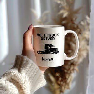 May include: White ceramic mug with the text "NO. 1 TRUCK DRIVER" and a black graphic of a semi-truck. The word "Name" is below the truck graphic. The mug has a curved handle.