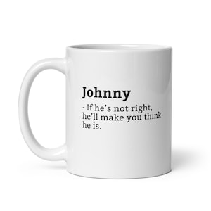May include: White ceramic mug featuring the name "Johnny" in black, accompanied by a humorous quote. The mug has a curved handle and a glossy finish, ideal for tea or coffee.