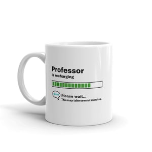 Könnte beinhalten: Eine weiße Keramik-Kaffeetasse mit einem schwarzen und grünen Design. Die Tasse trägt die Aufschrift "Professor lädt auf" mit einem Fortschrittsbalken und dem Text "Bitte warten... Dies kann einige Minuten dauern."