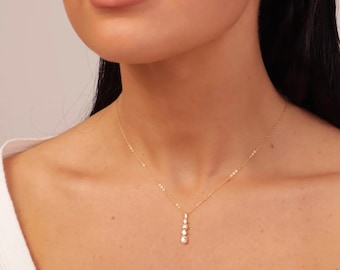 May include: A gold chain necklace with a pendant featuring a row of five clear round stones.